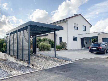 Einzelcarport von Siebau mit seitlichen Sichtschutzelementen. Aufbau auf Winkelstein-Mauer. E-Panel für bauseitige Ladestation